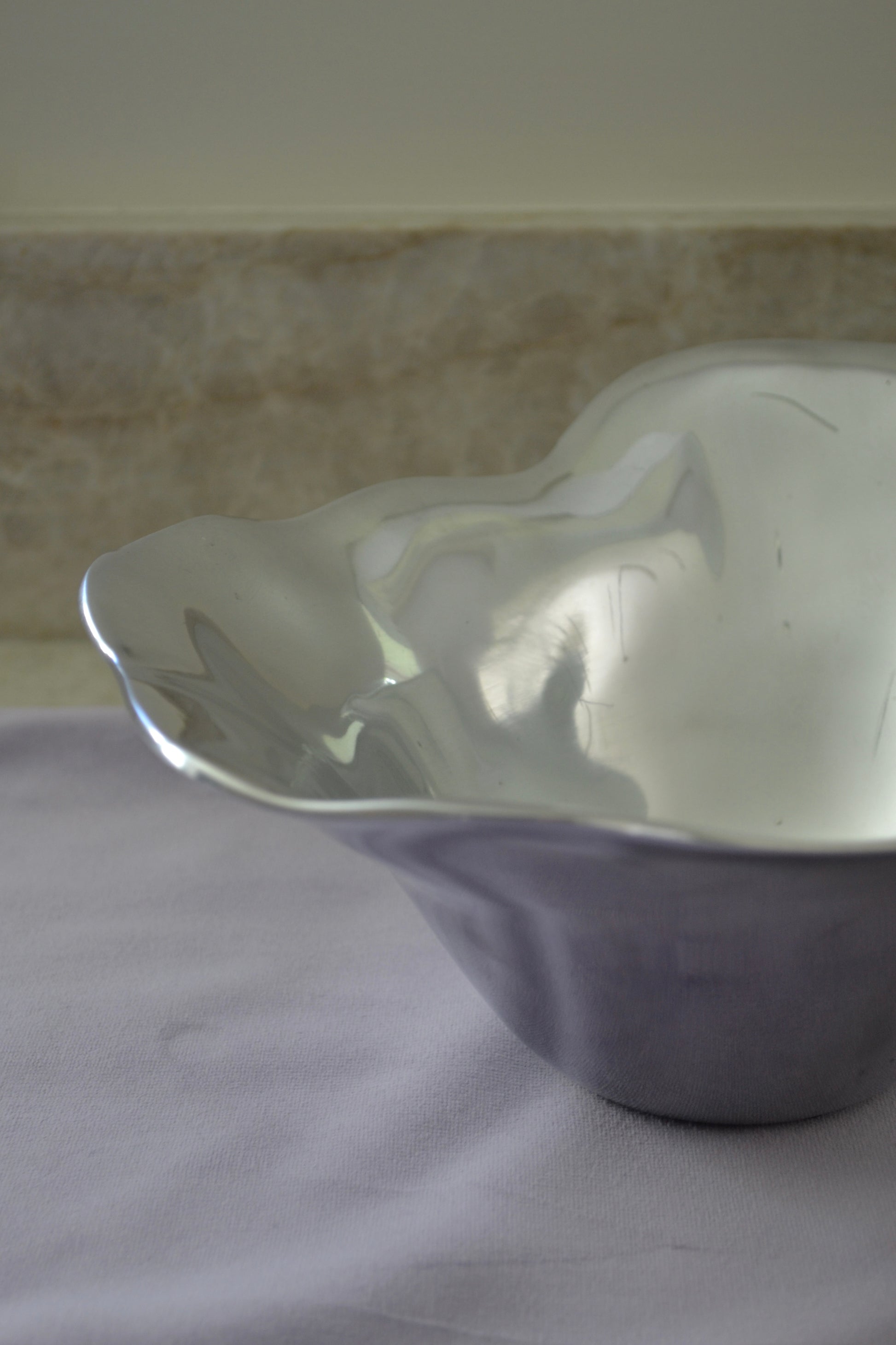 Silver bowl, freeform bowl, serving bowl, salad bowl, eclectic decor, kitchenware, kitchen bowl, funky home items, unique bowl, home decor, profile view.