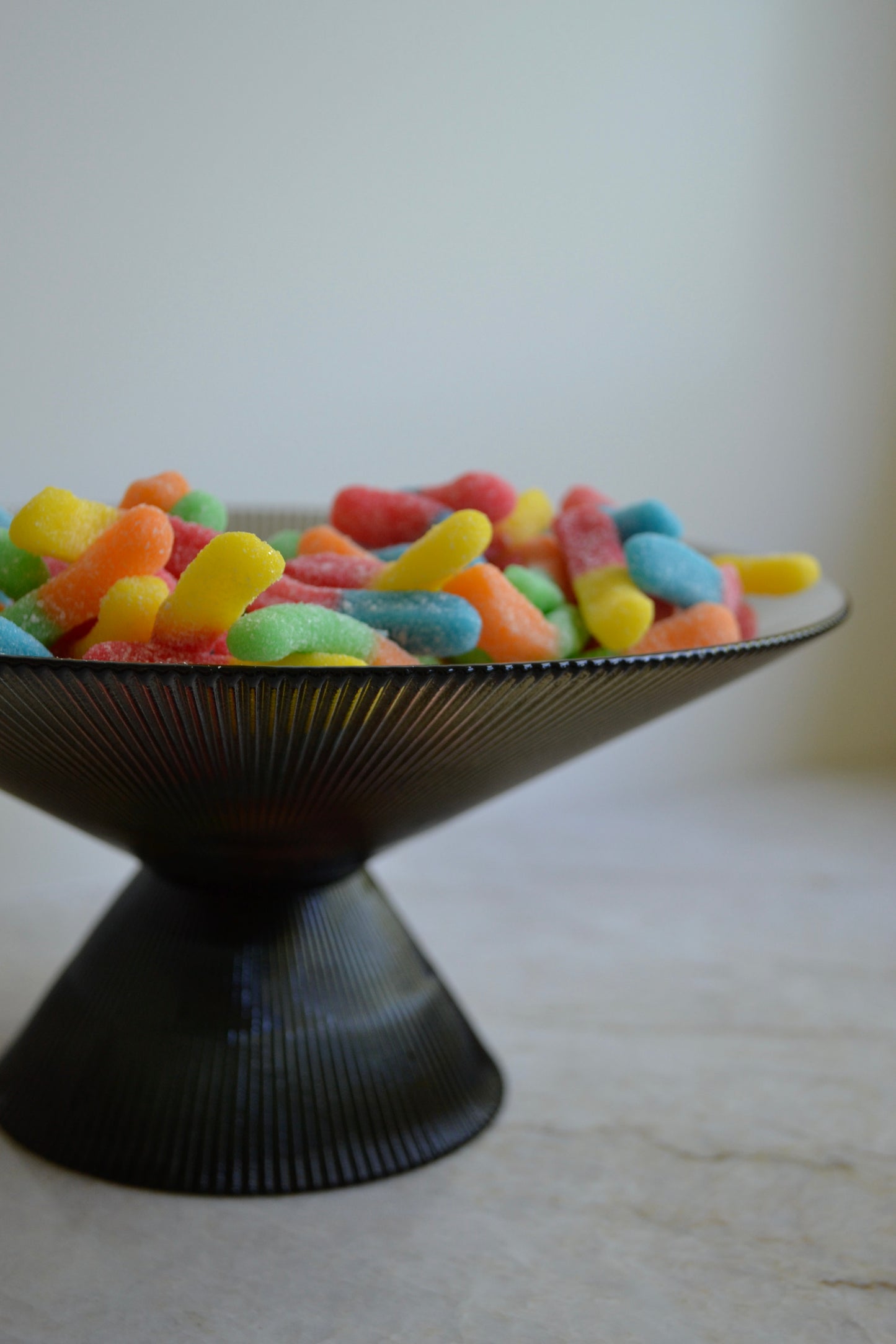 Glass bowl, footed bowl, serving bowl, fruit bowl, salad bowl, textured glass bowl, black glass bowl, eclectic decor, kitchenware, partial view.