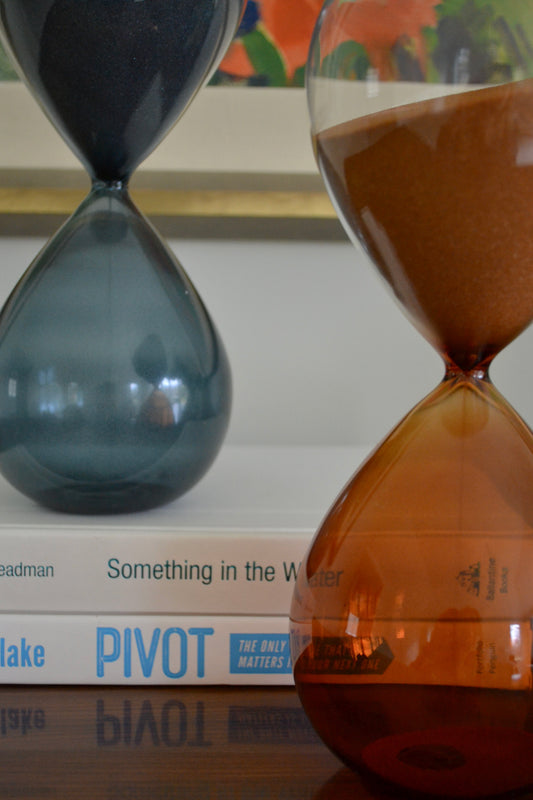 Hand-blown hourglass timer, blue hourglass, orange hourglass, sand timer, coffee table decor, shelf decor, zoomed in front view